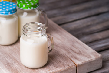 Milk jars with colorful caps on a cutting board 
