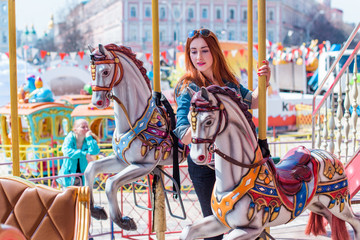 Adult girl has fun on the carousel and has a good time. The concept of fun in the city  