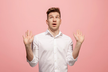 Beautiful male half-length portrait isolated on pink studio backgroud. The young emotional surprised man