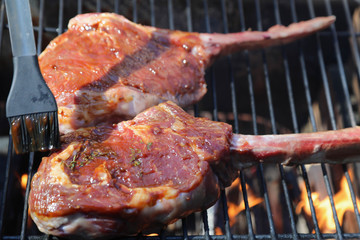 Tomahawk rib beef steak on hot black grill with flames
