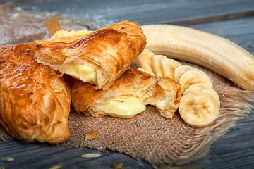 Puff pastry with a dough with a banana on a wooden table. Advertising still life from baking.