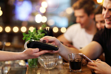 Group Of Friends Paying For Meal In Restaurant