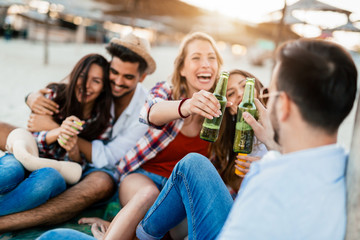 Happy couple smiling and drinking beer at beach