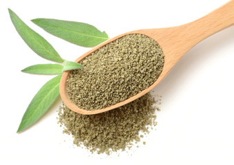 dried sage powder in the wooden spoon, isolated on white, top view