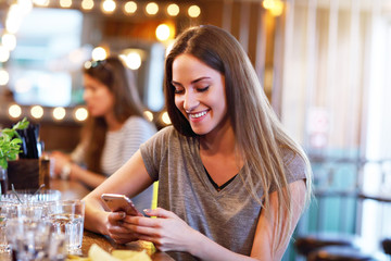 Happy woman texting in restaurant