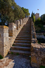 Lisbon, Portugal - February 1, 2013: Castelo de Sao Jorge aka Saint George Castle. Staircase on the Defensive walls with view of the wallwalk, battlements, ramparts, merlons and crenels in the towers