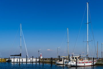 Sailboats moored by a pier in the harbor. Logos and id removed.