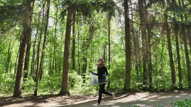 Young athletic girl in hijab running, jogging in green park, forest, front side view 50 fps