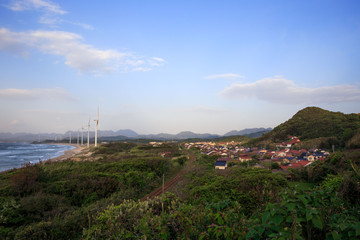 Fototapeta na wymiar Small coastal Japanese town with wind turbines on the beach