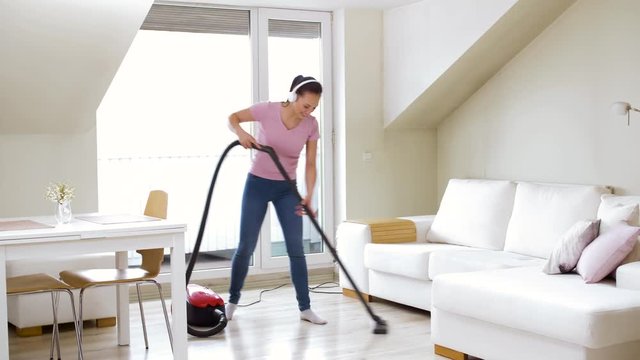 household, housework and cleaning concept - happy woman or housewife with vacuum cleaner and headphones dancing and singing at home
