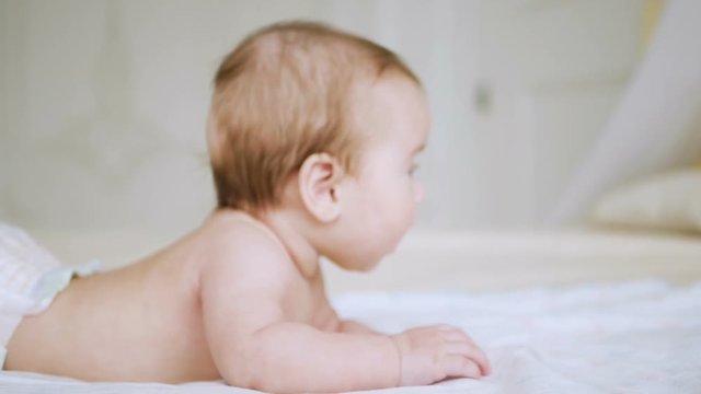 girl in a diaper without clothes lies on a large bed