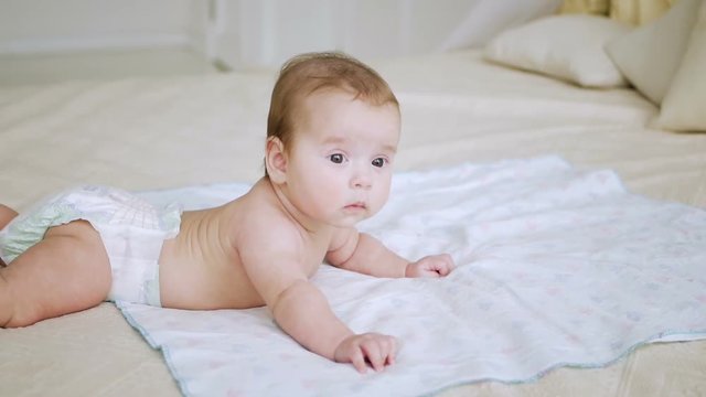 girl in a diaper without clothes lies on a large bed