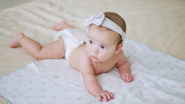 girl in a diaper without clothes lies on a large bed