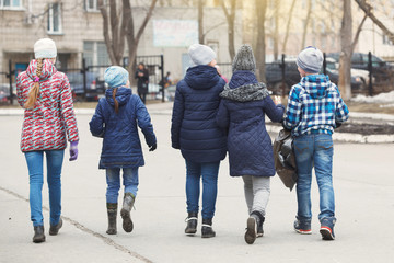 Children picking up trash in the schoolyard. The concept of environmental protection. Schoolboys carry black garbage bags.