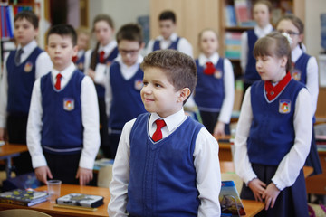 Pupils at the desk think and decide the task in the school. Primary education, training and people concept