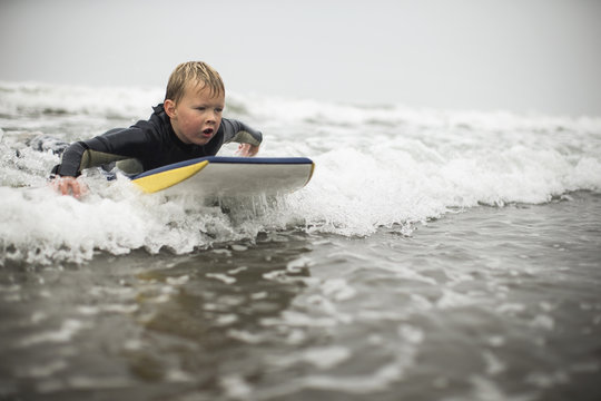 Boy riding bodyboard on waves in sea