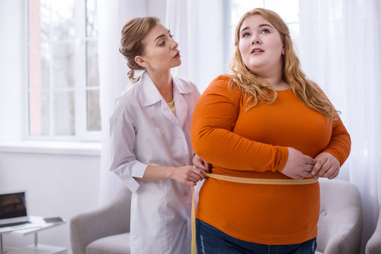 Big Weight. Serious Professional Doctor Talking With A Fat Woman And Measuring Her