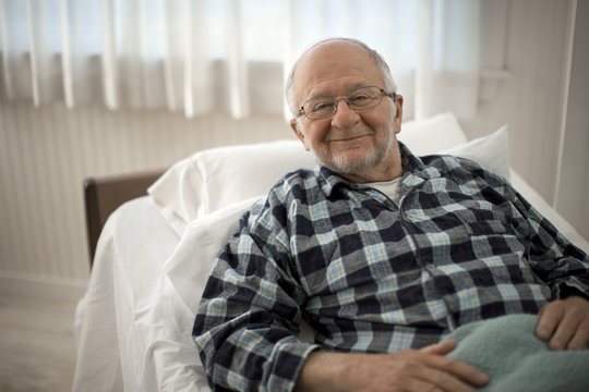 Portrait of a cheerful senior man lying in bed.