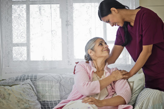 Smiling young nurse comforting an elderly woman.