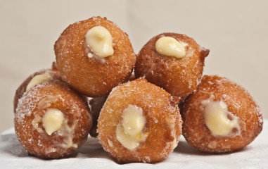 Front view, close up of five freshly baked, homemade lemon cream filled donuts on a white, round, display dish