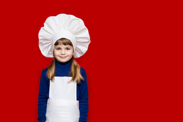 Portrait of beautiful little girl in form of cook isolated on red. Kid chef. Cooking Process Concept 