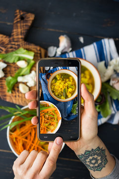 Phone photography of food. Woman hands take photo of lunch with smartphone for social media. Lentil soup with cauliflower. Raw vegan vegetarian healthy dinner 