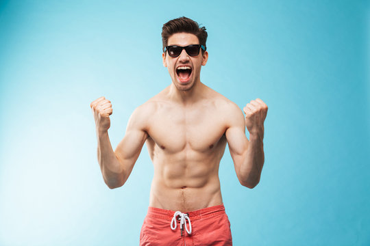 Portrait of a cheerful young shirtless man in swimming shorts
