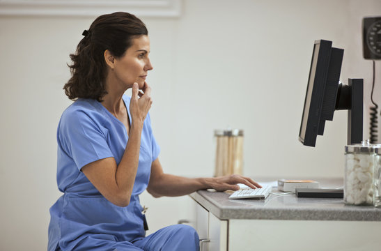 Contemplative nurse using a computer inside an office.