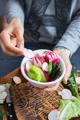 Woman hands holding fresh summer vegetables cut in bowl. Veggie cucumber, radish, laminaria seaweed, cabbage, zucchini for dinner or lunch. Raw vegan vegetarian heathy food.