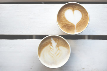 Two paper cups of coffee take-away on wooden table with copy space. Top view.