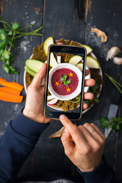 Phone photography of food. Woman hands take photo of lunch with smartphone for social media. Beetroot soup. Traditional Russian borscht. Raw vegan vegetarian healthy dinner 