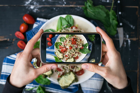 Phone photography of food. Woman hands take photo of lunch with smartphone for social media. Fresh vegetables salad. Cabbage salad with tomatoes. Raw vegan vegetarian healthy dinner 