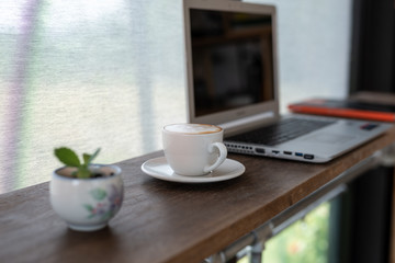Obraz premium Coffee cup and laptop for business on the table in the coffee shop. Selective focus on coffee.