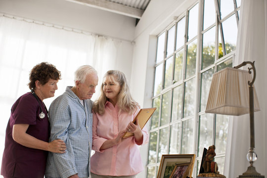Mature woman and nurse showing old family photographs to a senior man.