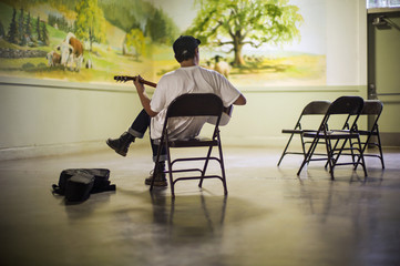 Teenage boy playing an acoustic guitar in front of a mural.