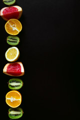 Fitness bottle of water and different fruits on black table. Background layout with free text space.