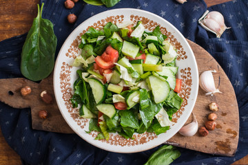 Fresh vegetables salad. Mediterranean salad with spinach, basil, tomatoes, cucumbers, nuts. Raw vegan vegetarian healthy food on lunch or dinner