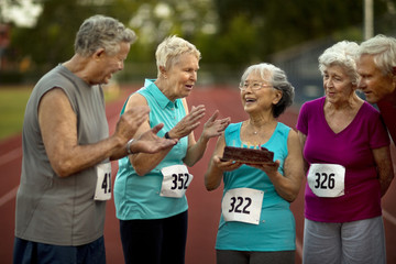 Happy senior friends celebrate a birthday before an athletics event.