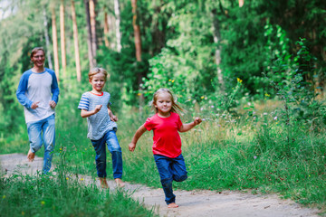 Obraz premium happy family - father with two kids - run play in nature