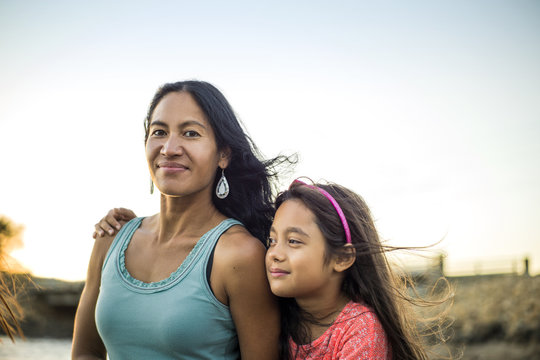 Smiling mother and daughter standing outdoors