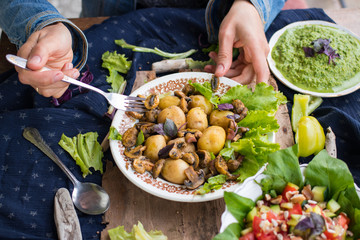 Woman hands holding backed potatoes and roasted mushrooms on salad leaves. Organic farm lunch or dinner. Raw vegan vegetarian healthy food