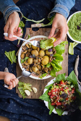 Woman hands holding backed potatoes and roasted mushrooms on salad leaves. Organic farm lunch or dinner. Raw vegan vegetarian healthy food