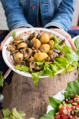 Woman hands holding backed potatoes and roasted mushrooms on salad leaves. Organic farm lunch or dinner. Raw vegan vegetarian healthy food