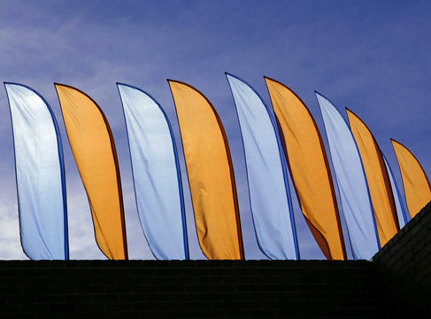 Blue and yellow beach flags against a blue sky