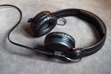 Black audio hipster headphones with cord lying on grey background