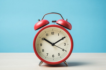 Red vintage alarm clocks on wooden table and light blue background wall