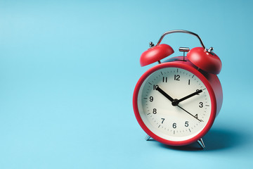 Red vintage alarm clock on light blue color background