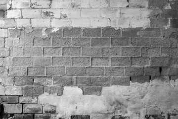 Full frame background of old and rough concrete block wall which is partly plastered or painted. Copy space. Black and white.