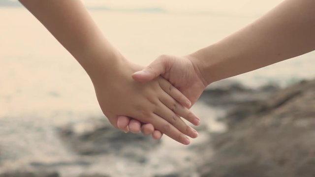 Slow motion couple Women and men Join hands on the beach to feel warm. Romantic and loving  .as background Valentine concept with copy spaces for your text or design.