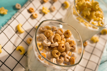 angle view two cups of milk with cereal rings in a sunny morning as healthy breakfast